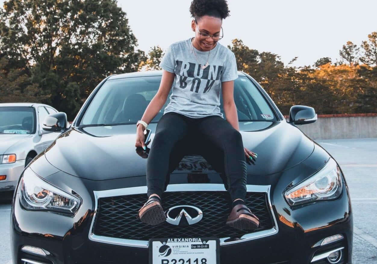 teen sitting on the hood of a black car