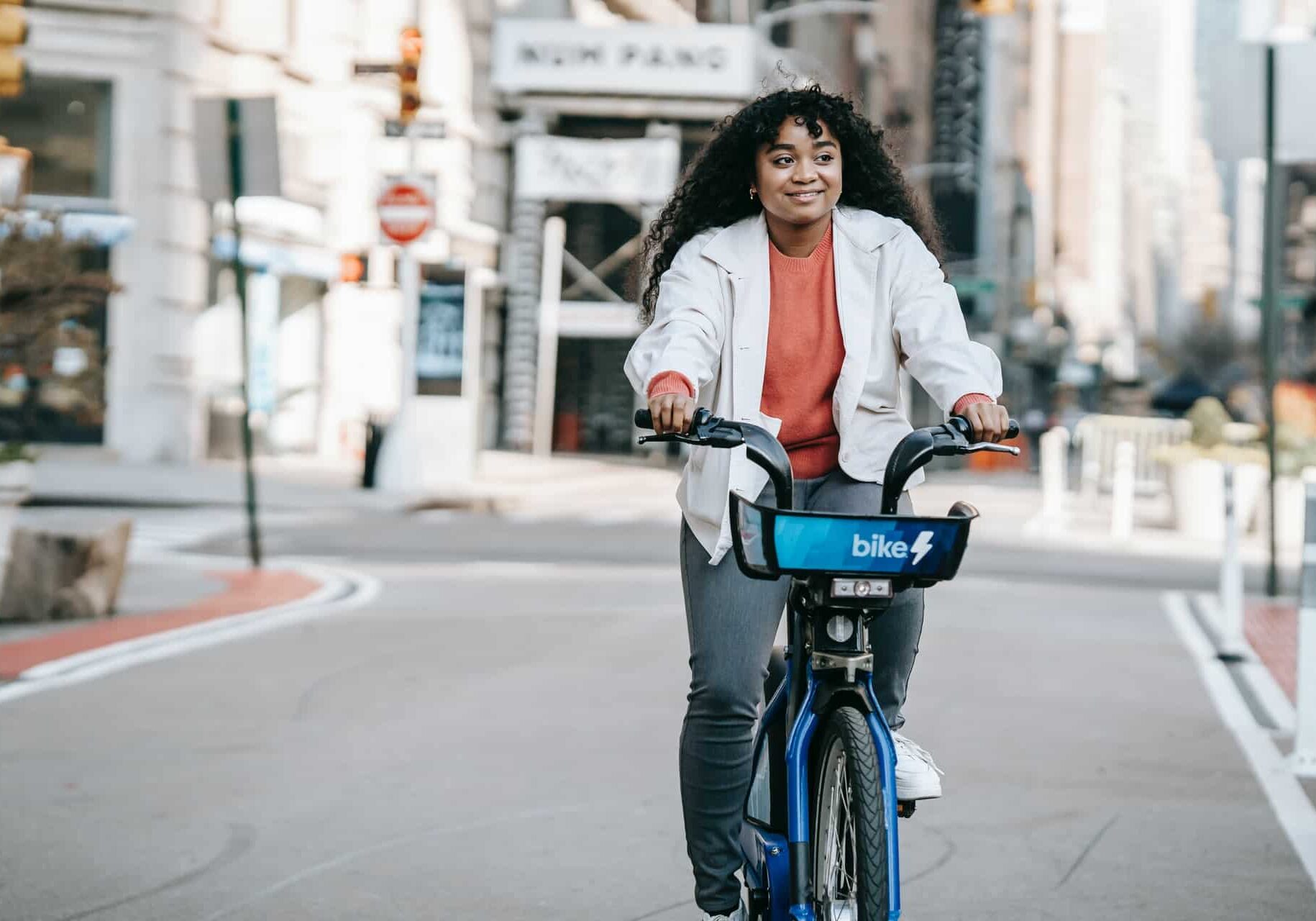 a black woman happily riding a bike