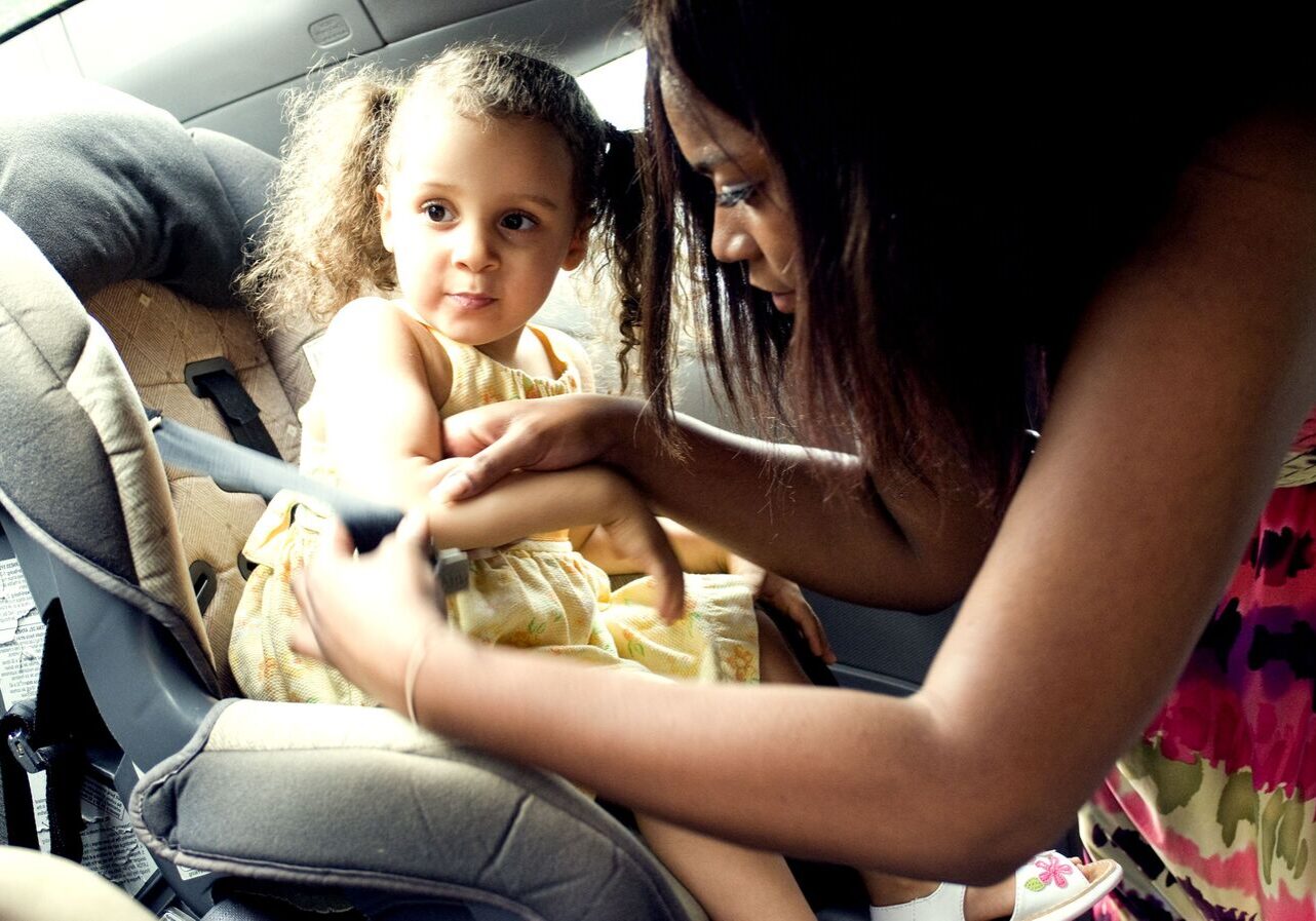 a mother placing child in a car seat